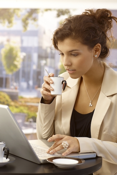 Kvinna med en espresso på sin bärbara dator.