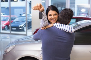 A woman looking at the camera, smiling, and holding car keys.