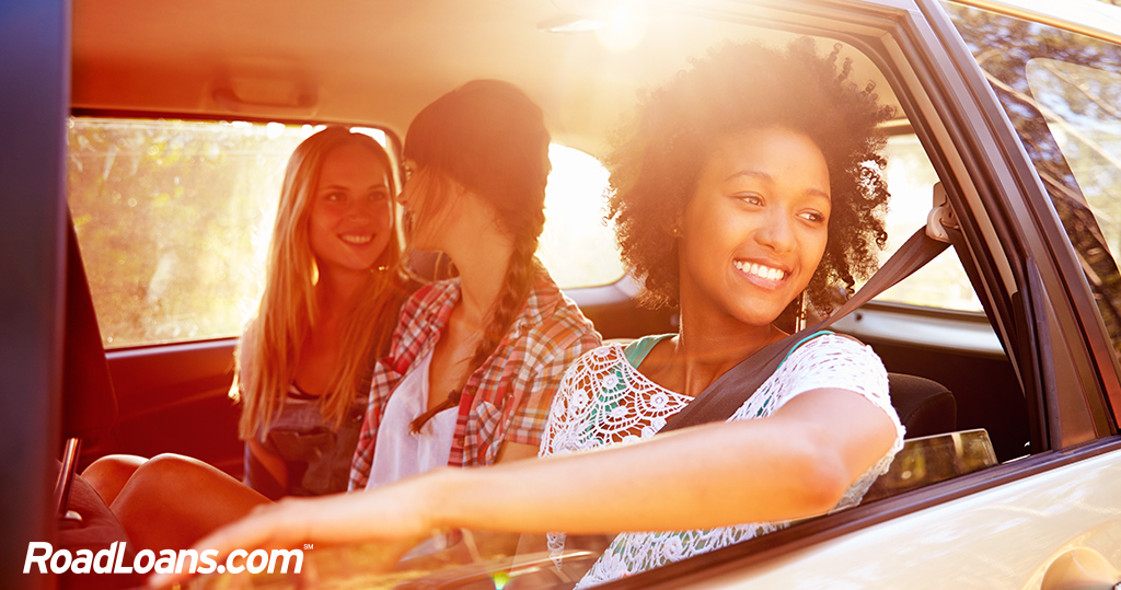 Tre vänner i baksätet på en bil, ler och har roligt.